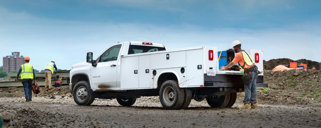 White Chevrolet Silverado 3500 HD Regular Cab chassis cab with a utility body and dual rear wheels at a construction site